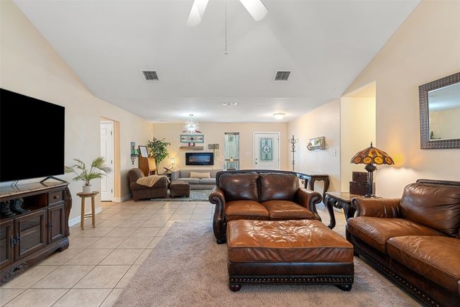 Living room featuring light tile patterned flooring, ceiling fan, lofted ceiling, and baseboards | Image 13
