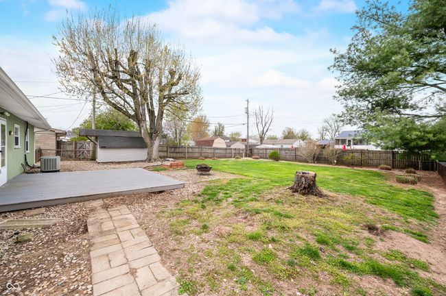 view of yard featuring central AC unit, a deck, an outdoor fire pit, a fenced backyard, and an outdoor structure | Image 11
