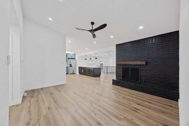 Unfurnished living room with ceiling fan, light wood-style floors, a brick fireplace, and recessed lighting | Image 5