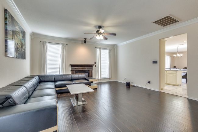 Living area with ornamental molding, wood finished floors, and ceiling fan with notable chandelier | Image 7