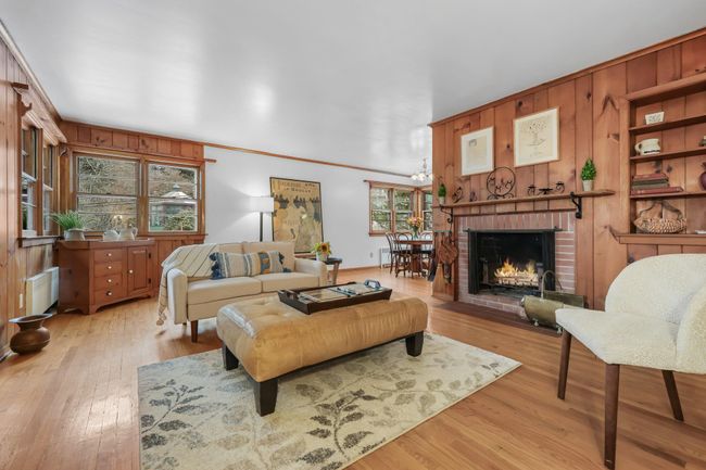 Living room with a wood burning fireplace and hardwood flooring | Image 11