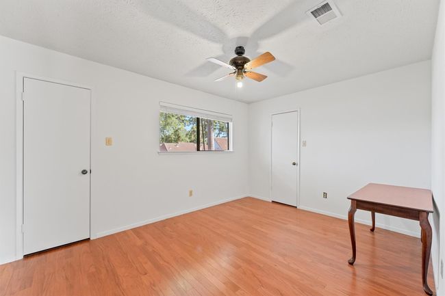 Experience comfort and style in this inviting bedroom featuring hardwood floors, ample natural light, and a ceiling fan for year-round comfort. | Image 18