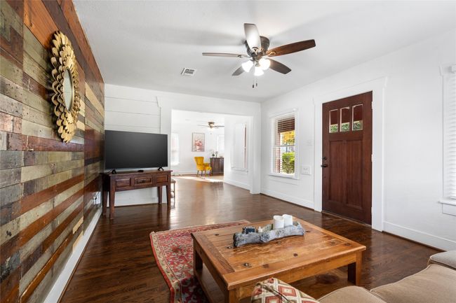 Living room featuring ceiling fan, wooden walls, and wood finished floors | Image 7