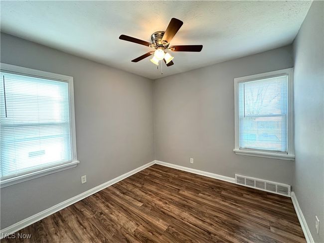 Spare room with baseboards, plenty of natural light, visible vents, and dark wood-style floors | Image 7