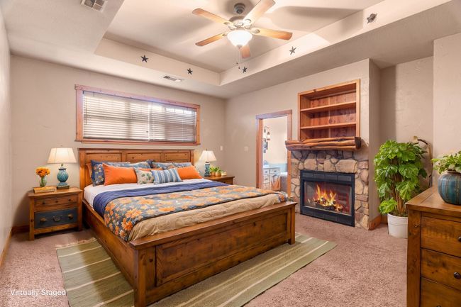 Bedroom with a fireplace, carpet flooring, visible vents, and a tray ceiling | Image 32