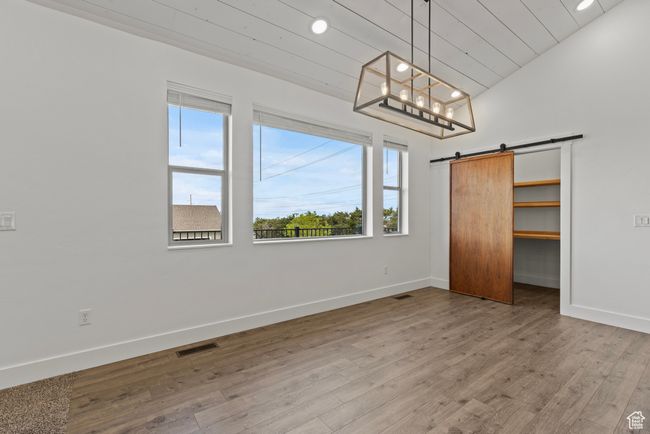 Unfurnished bedroom with baseboards, wood finished floors, a barn door, a spacious closet, and recessed lighting | Image 12