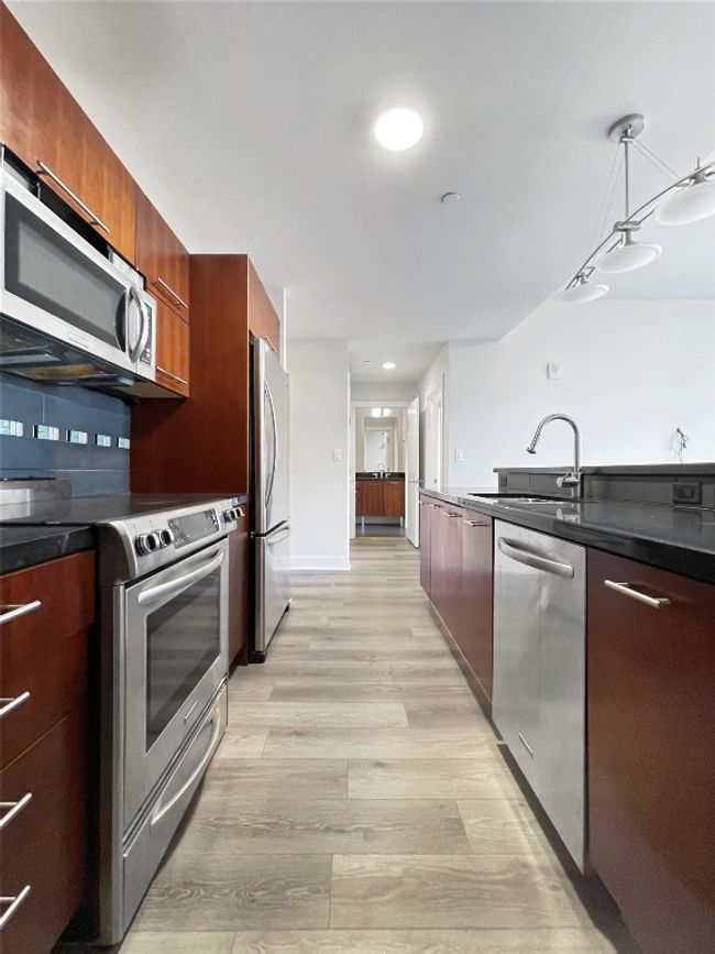 Kitchen featuring stainless steel appliances, modern cabinets, a sink, light wood finished floors, and pendant lighting | Image 11