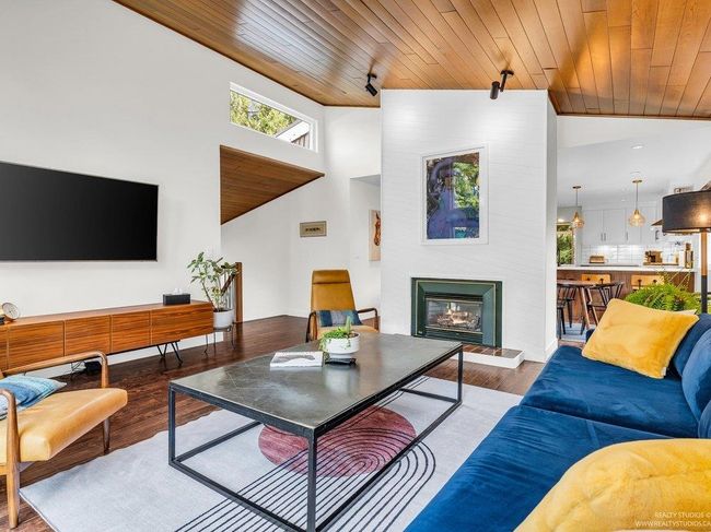 Spacious open concept living Room with vaulted warm wood ceiling, full height west facing (new) windows flooding the room with natural light, and a cozy gas fireplace as a central focal point in the 'Great Room'. | Image 11