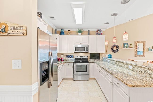 Kitchen with appliances with stainless steel finishes, a peninsula, and white cabinetry | Image 17
