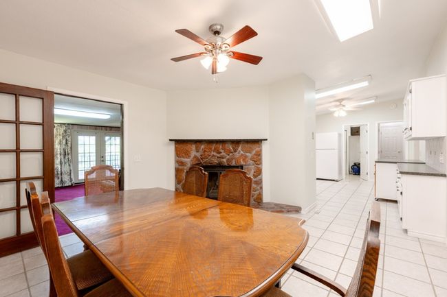Dining area with a ceiling fan, light tile patterned flooring, a fireplace, and french doors | Image 16
