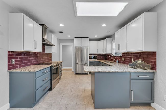 Kitchen with stainless steel finishes, white and blue cabinetry and peninsula | Image 6