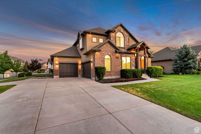 Traditional-style house featuring a garage, a front yard, driveway, stone siding, and stucco siding | Image 38