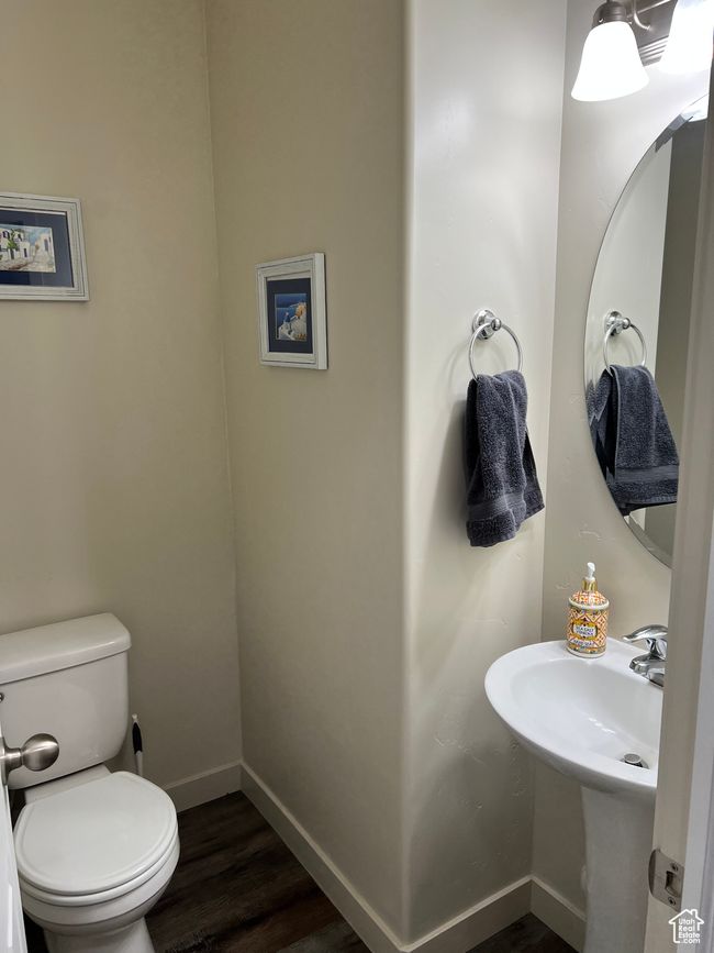 Half bathroom with baseboards, wood finished floors, toilet, and a sink | Image 15