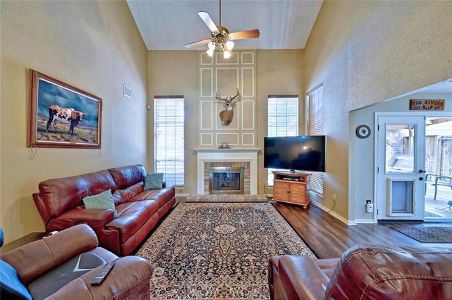 Expansive family room with soaring two-story ceilings, cozy fireplace, and abundant natural light. Perfect for gatherings and relaxation. | Image 8
