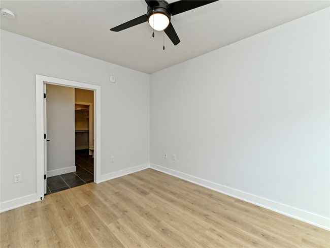 Unfurnished room featuring light wood finished floors, ceiling fan, baseboards, and a smoke detector | Image 6