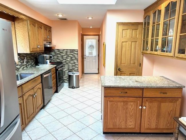 Kitchen featuring light stone countertops, appliances with stainless steel finishes, backsplash, and light tile patterned flooring | Image 4