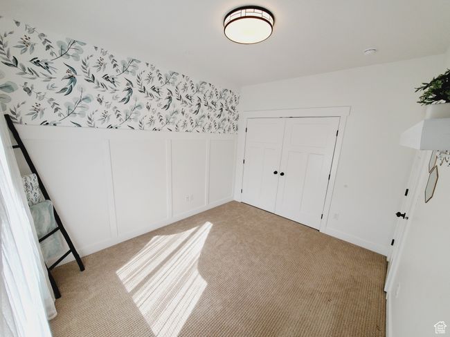 Unfurnished bedroom featuring a closet, light colored carpet, and a decorative wall | Image 17
