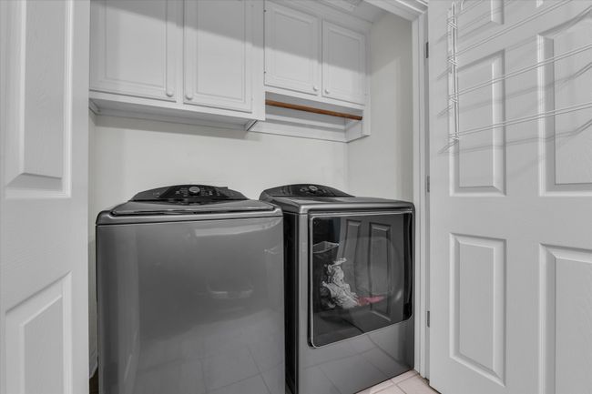 Laundry room featuring cabinet space, washer and dryer, and light tile patterned floors | Image 29