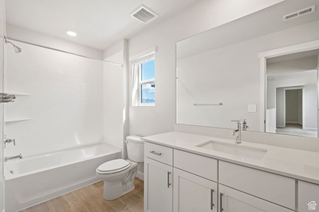 Bathroom with toilet, wood finished floors, vanity, shower / washtub combination, and recessed lighting | Image 24