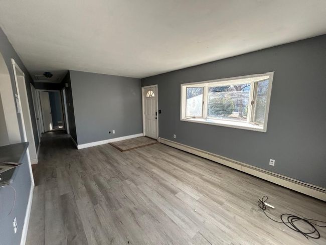 Unfurnished living room featuring a baseboard heating unit and light hardwood / wood-style floors | Image 7