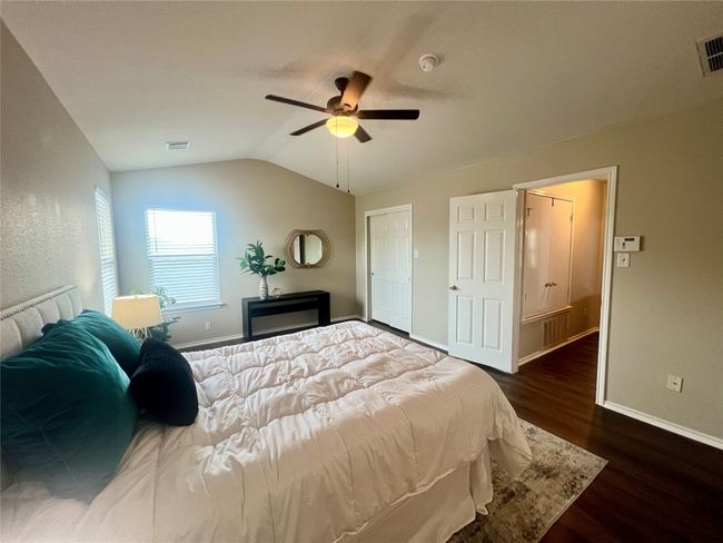 Bedroom with wood finished floors, baseboards, lofted ceiling, and a ceiling fan | Image 20