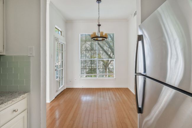 Unfurnished dining area with light wood-style flooring, visible vents, crown molding, and baseboards | Image 11