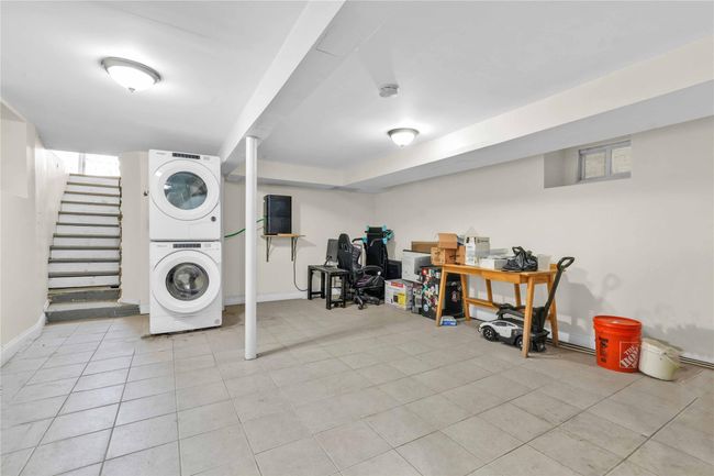 Clothes washing area featuring stacked washer / dryer, light tile patterned floors, laundry area, and baseboards | Image 12
