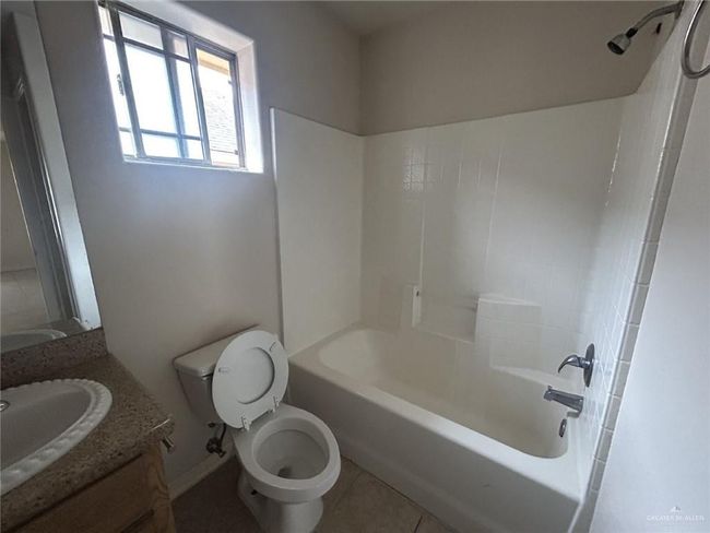 Bathroom with tile patterned floors, toilet, vanity, tub / shower combination, and baseboards | Image 6