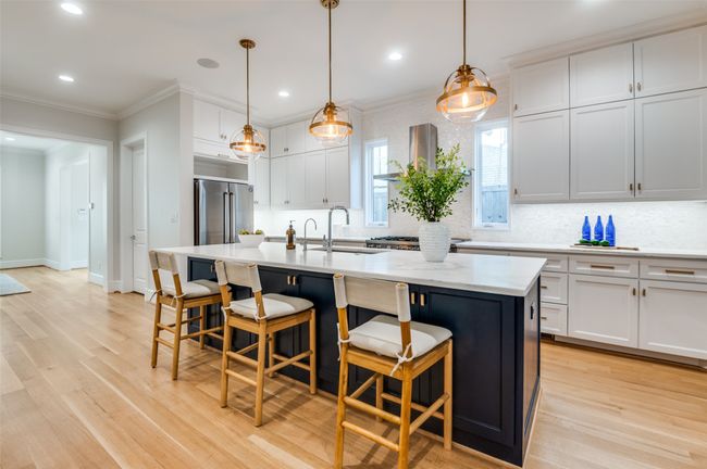 Kitchen featuring light wood finished floors, crown molding, a sink, and freestanding refrigerator | Image 9