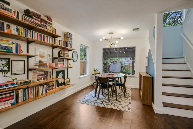 Dining area with updated modern light fixture and custom mounted bookshelves. | Image 7