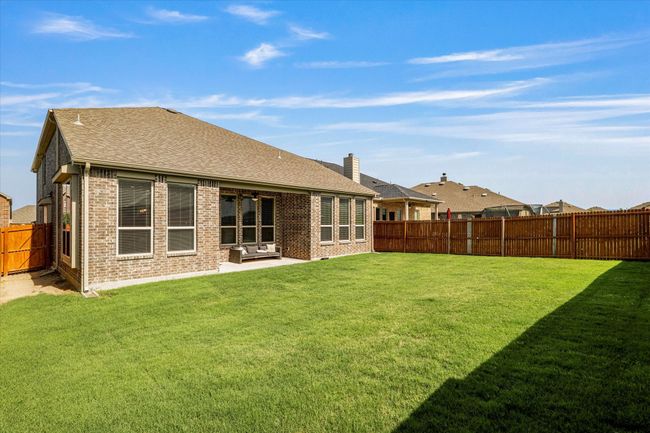 Back of property with brick siding, a patio, a chimney, and a shingled roof | Image 38