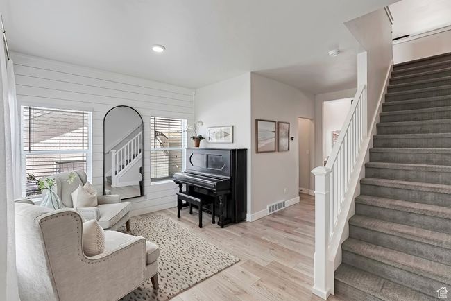 Living area with stairs, light wood finished floors, wooden walls, baseboards, and recessed lighting | Image 10