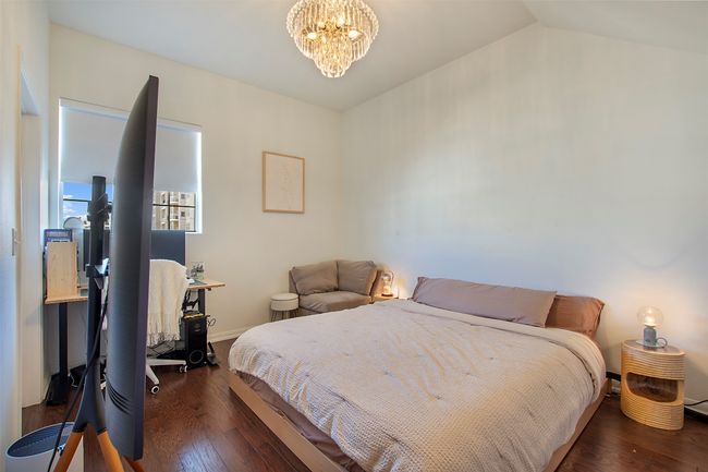 Bedroom with a chandelier, wood finished floors, vaulted ceiling, and baseboards | Image 15