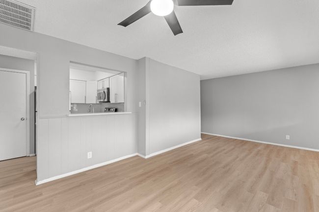 Unfurnished living room with light wood finished floors, visible vents, a sink, baseboards, and ceiling fan | Image 6