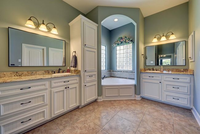 Primary Bathroom featuring large walk-in shower with double vanity, cozy bathtub nook with windows and 2 walk-in closets. | Image 17