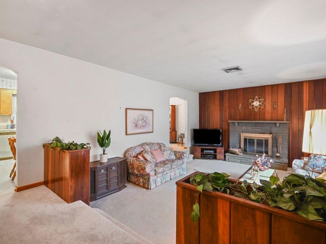 Carpeted living room with wood walls and a fireplace | Image 12