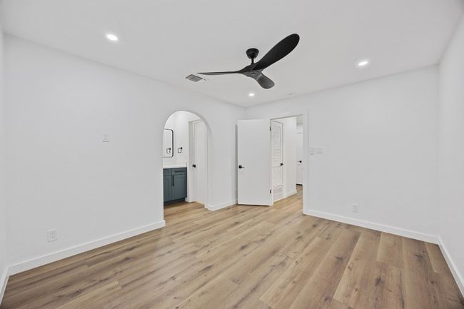 Unfurnished bedroom featuring arched walkways, light wood finished floors, recessed lighting, ensuite bath, and a ceiling fan | Image 18