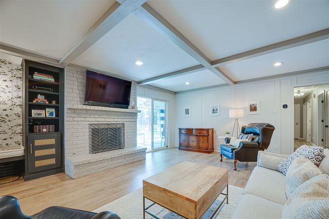 Living area with beam ceiling, wood finished floors, recessed lighting, and a fireplace | Image 9