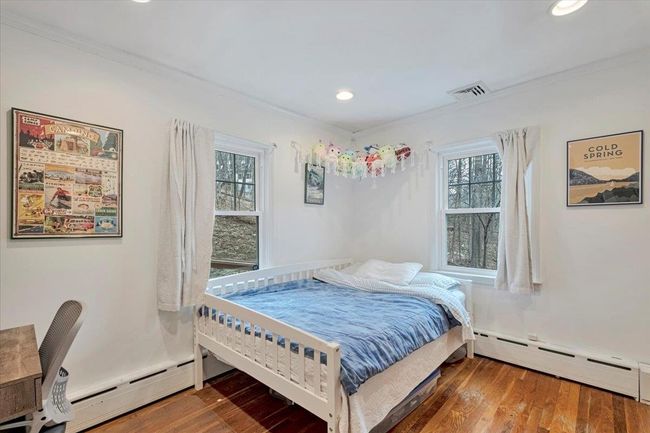 Bedroom with crown molding, wood finished floors, a baseboard heating unit, and baseboard heating | Image 14