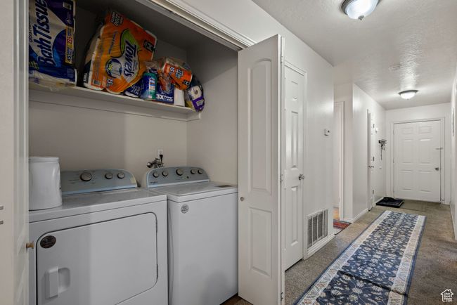 Laundry room featuring washer and clothes dryer and light colored carpet | Image 55