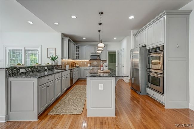 Kitchen equipped with stainless steel appliances, double wall ovens, newer dishwasher and microwave, and abundant cabinetry for optimal storage and functionality. | Image 24