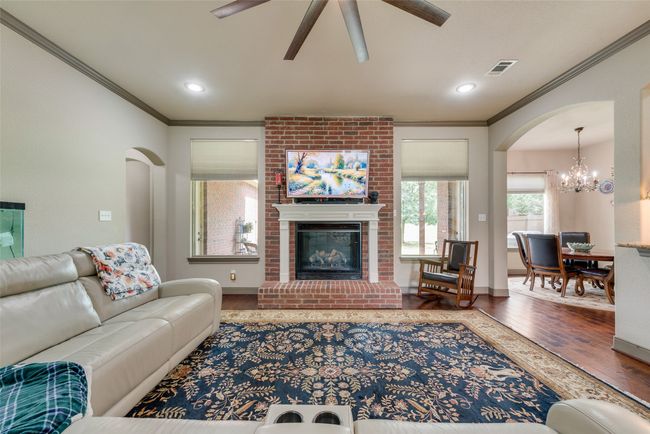 Living room featuring wood finished floors, ornamental molding, a ceiling fan, a chandelier, and arched walkways | Image 13
