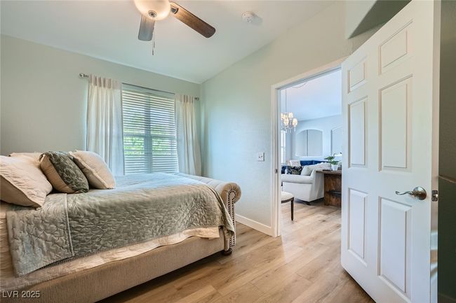 Bedroom featuring ceiling fan with notable chandelier, light wood-style flooring, and baseboards | Image 14