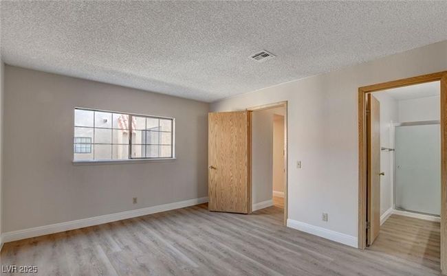 Unfurnished bedroom with wood finished floors, a textured ceiling, and baseboards | Image 8