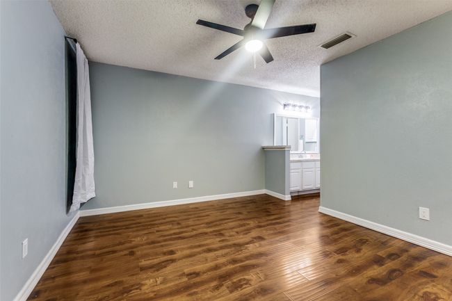 Empty room featuring a textured ceiling, dark wood-type flooring, and a ceiling fan | Image 21