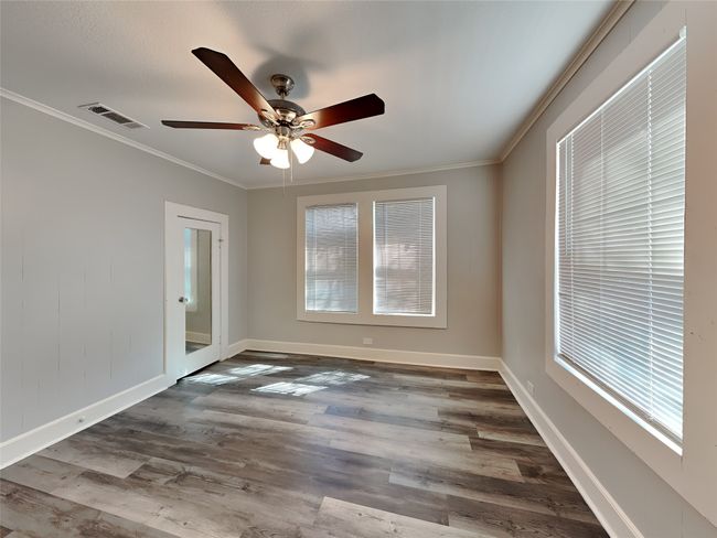 Spare room with plenty of natural light, dark wood-style floors, ceiling fan, ornamental molding, and baseboards | Image 9