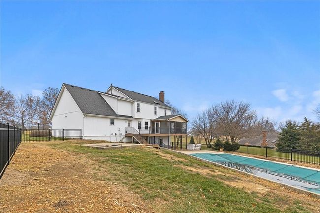 Back of house featuring a sunroom, a patio area, a yard, and a covered pool | Image 38