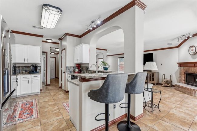 Kitchen with a breakfast bar, crown molding, and white cabinetry | Image 12