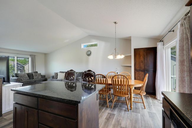 The granite topped center island features extra cabinet space, and drawers, a convenient breakfast bar, and plenty of room for entertaining and meal prep. | Image 12