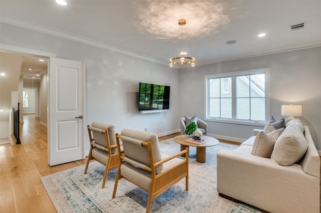 Living room with visible vents, a notable chandelier, light wood-style floors, and ornamental molding | Image 6